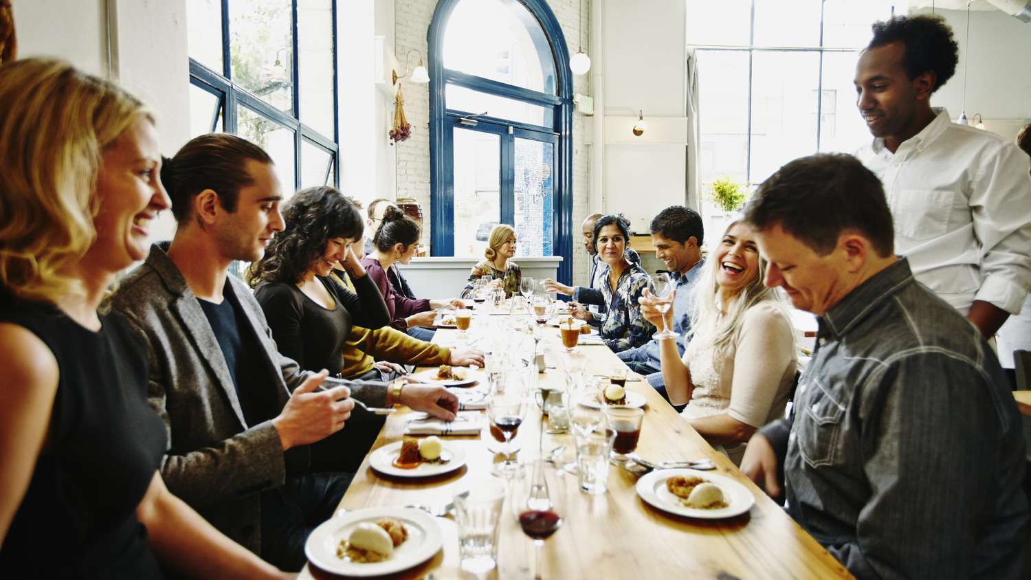 A couple sits at a restaurant table with two relatives, talking over a simple meal.