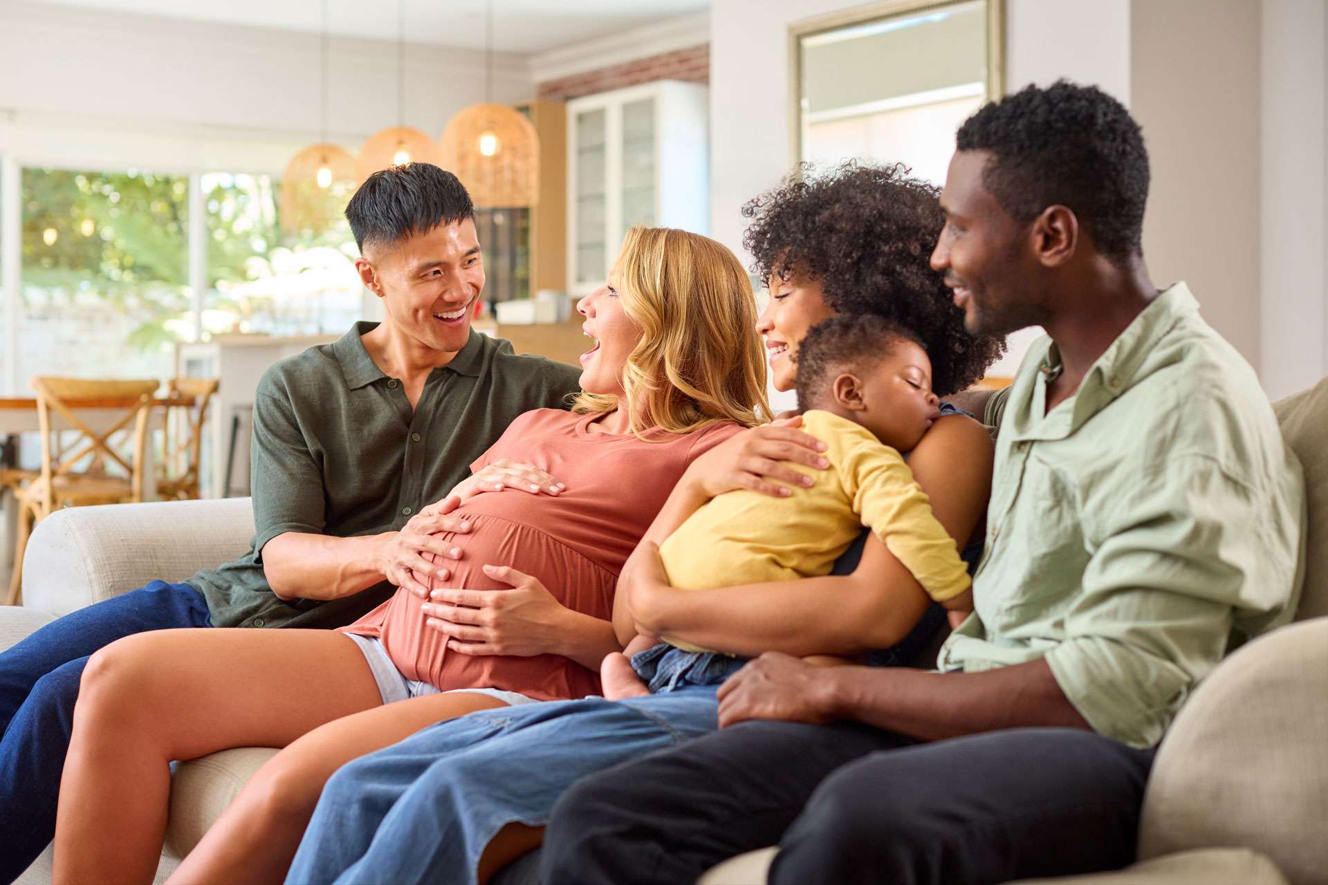 A couple sitting at a kitchen table with calendars and a notebook open, talking calmly while planning an upcoming family visit