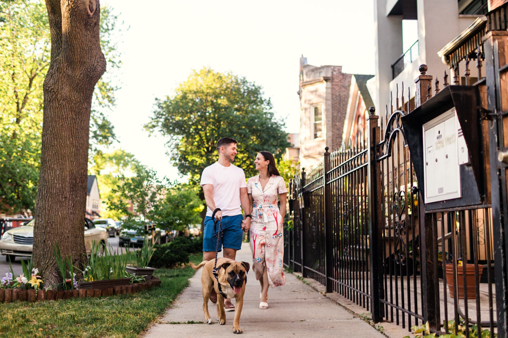 A couple walking side by side on a quiet neighborhood sidewalk at dusk, talking with relaxed body language and an easy pace