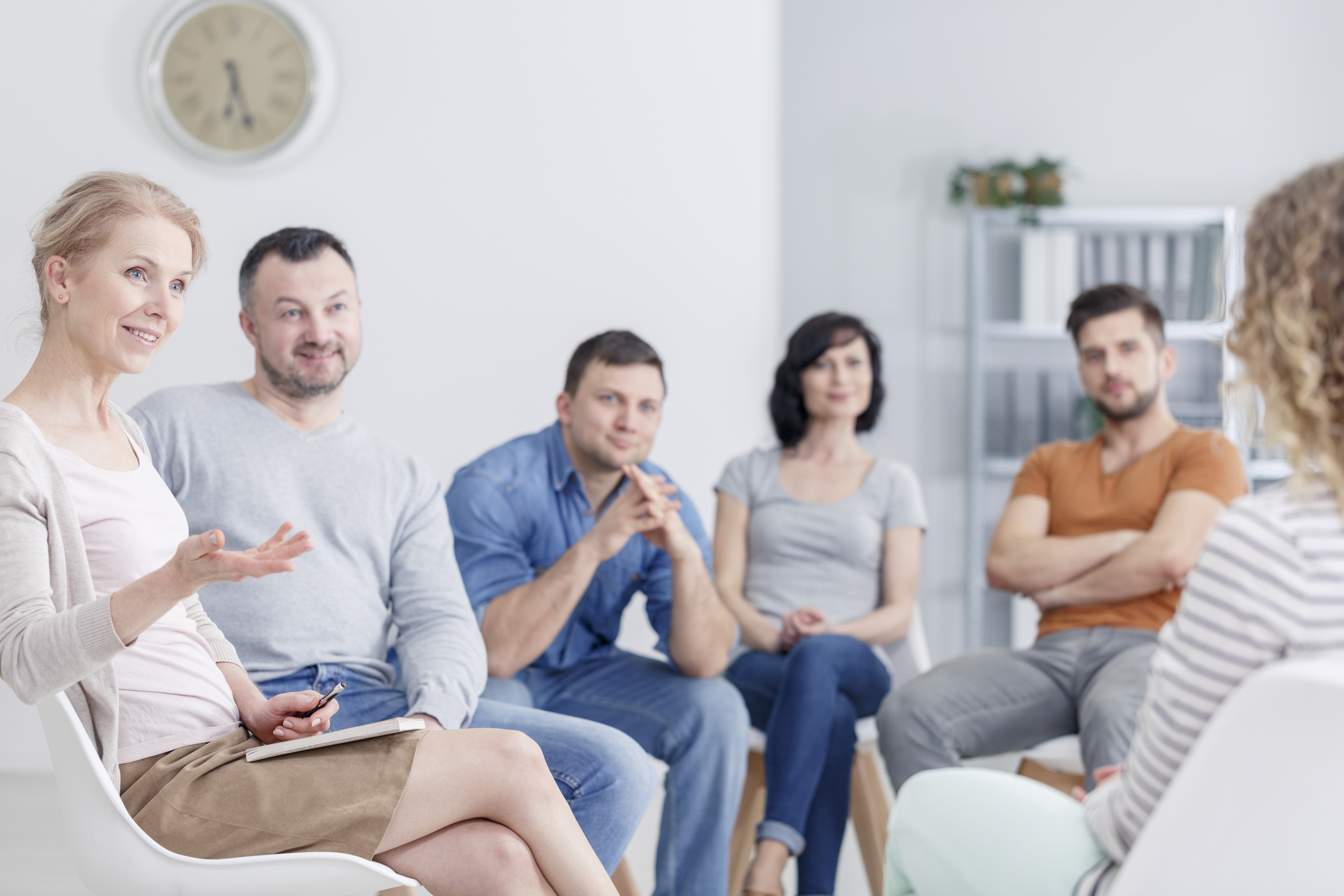 A family sitting in a living room during a conversation, with a teenager listening while a parent speaks