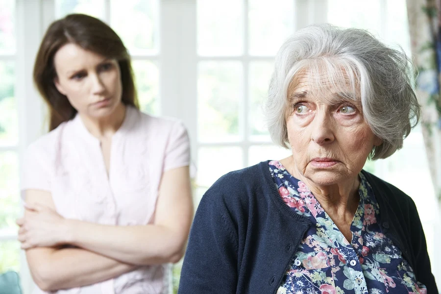 A grandmother and a parent having a tense conversation at a front doorway while a child stands nearby, candid family moment