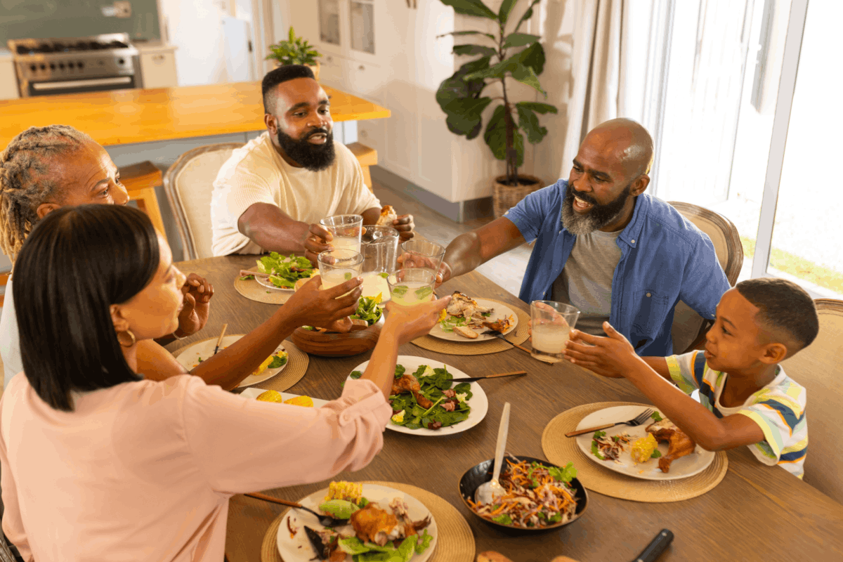 A multigenerational family seated at a kitchen table having a calm conversation, neutral expressions, everyday home setting