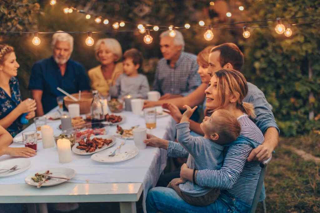 A multigenerational family sitting around a dinner table in a cozy home, talking and listening with relaxed expressions