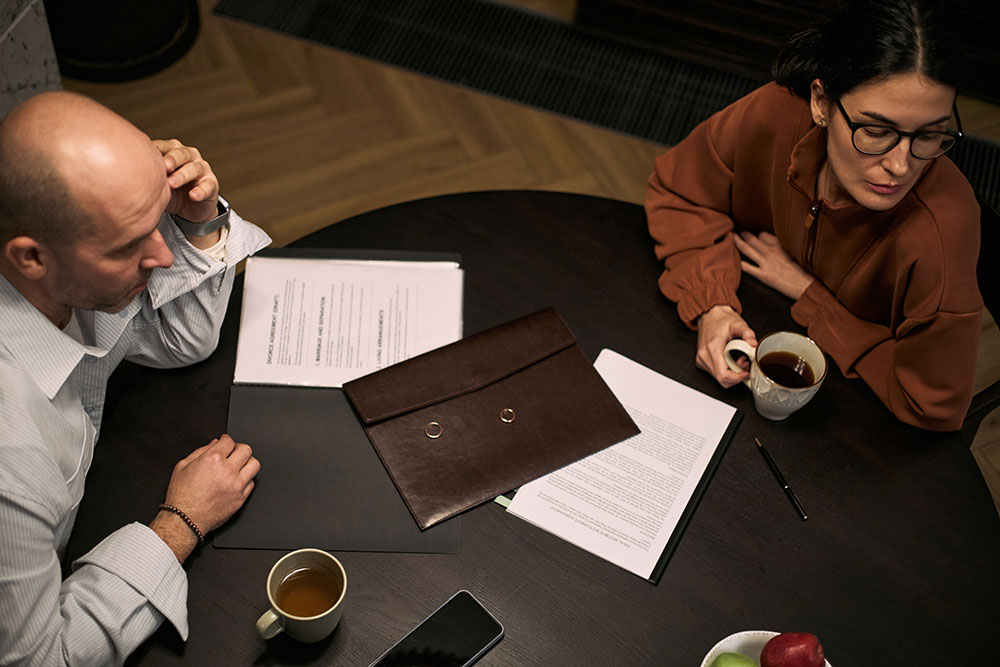 A person sitting across from a family law attorney, reviewing a folder of documents on a desk