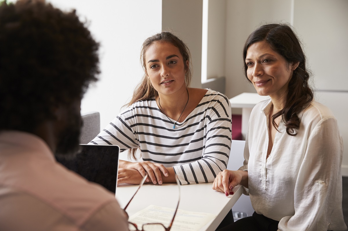 A school counselor speaking with a parent in a small office at an elementary school