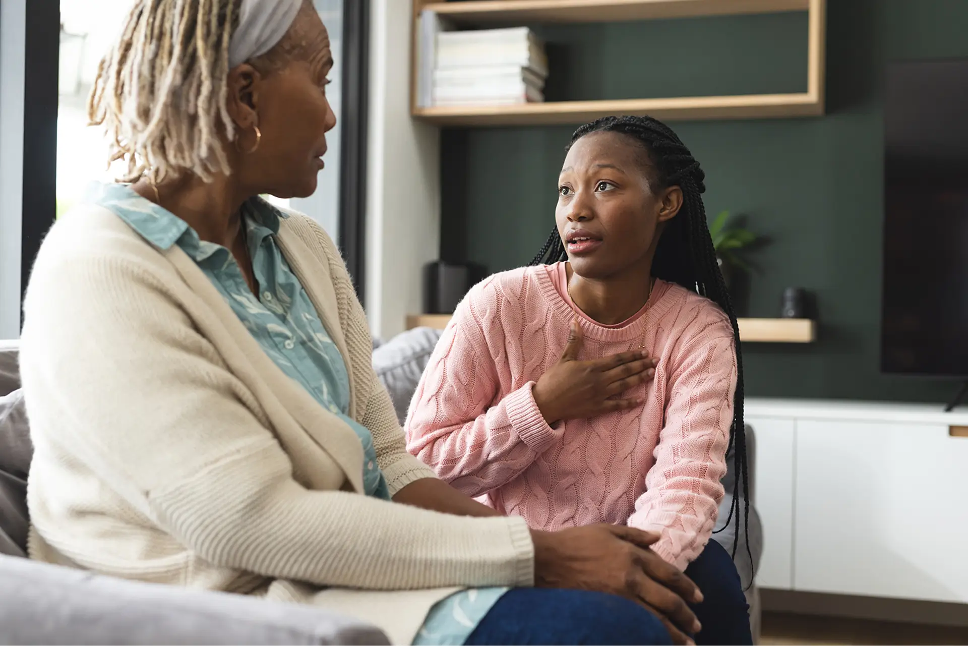 An adult child sitting at a kitchen table, speaking calmly with an older parent during a serious but respectful conversation in a warmly lit home