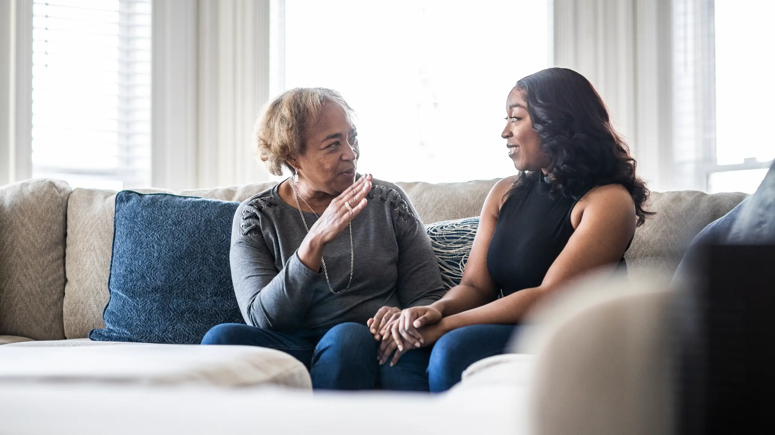 An adult daughter and her mother talking while seated in a living room